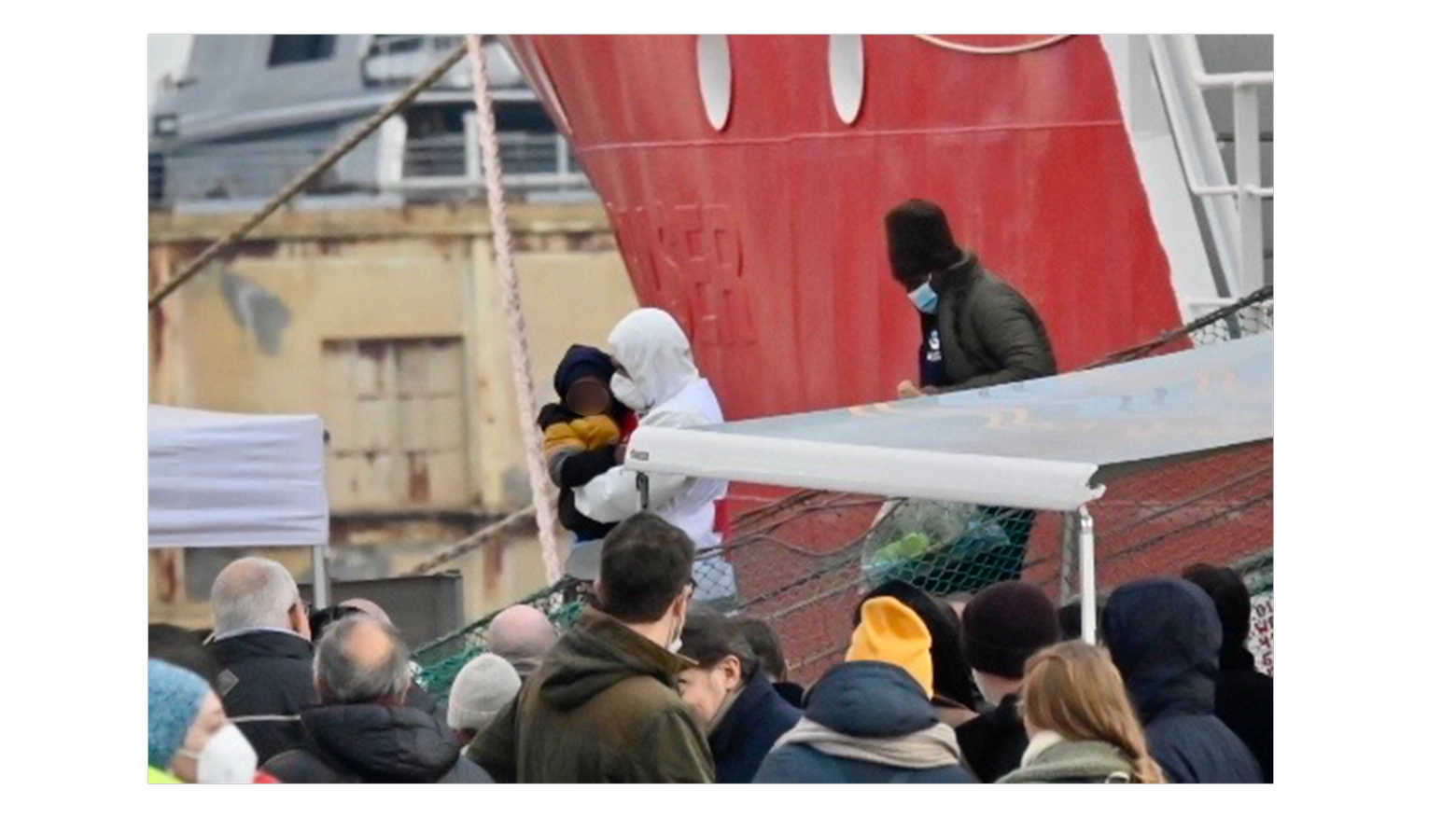 Un volontario scende dalla nave di Emergency tenendo stretto un bambino (Foto Novi)
