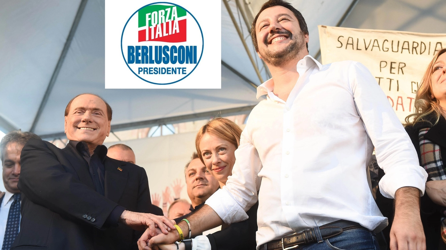 Berlusconi, Meloni e Salvini in una foto d'archivio (Newpress). In alto il logo di FI