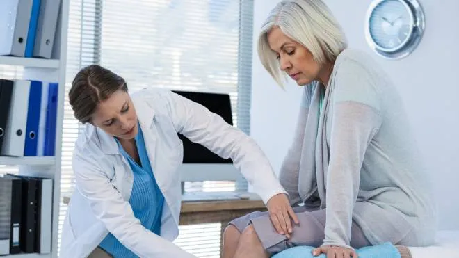 Doctor examining patient knee in clinic