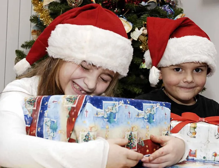 I bambini abbracciano i regali che trovano sotto l’albero di Natale