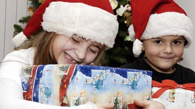 I bambini abbracciano i regali che trovano sotto l’albero di Natale